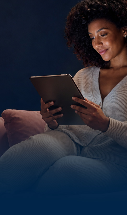 Femme consultant une tablette le soir, installée dans un canapé
